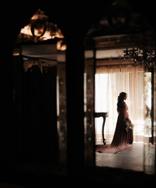 Woman performing a serene yoga pose in a dark room with teal light.
